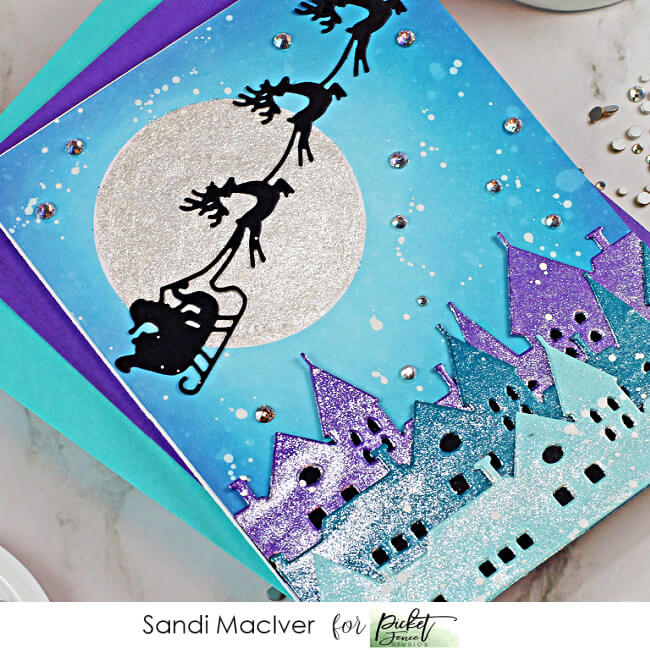 handmade christmas card with a village and santa and reindeer up iin the sky, cardmaking supplies from Picket Fence Studios
