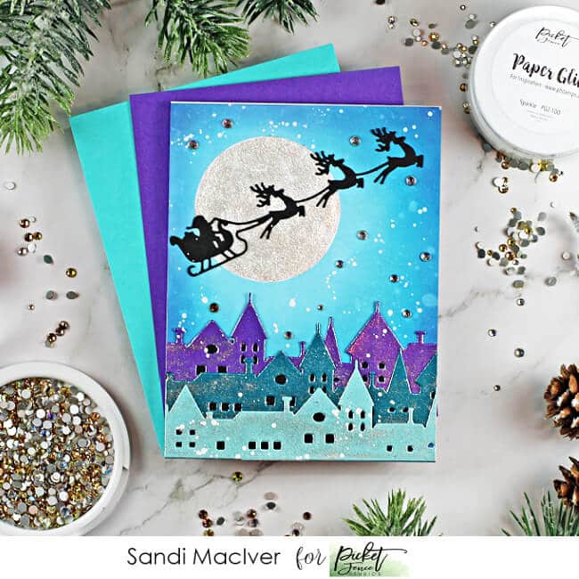 handmade christmas card with a village and santa and reindeer up iin the sky, cardmaking supplies from Picket Fence Studios