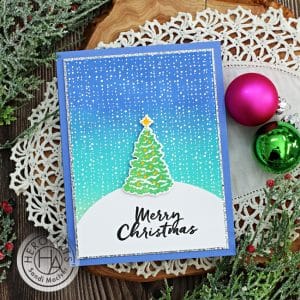 handmade christmas card with a ink blended background and a pretty tree in the snow using new card making products from Hero Arts