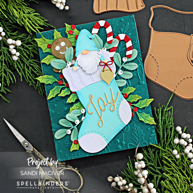 hand made christmas card with a dark green background, blue stocking full of christmas cheer created with card making products from Spellbinders