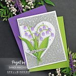 hand made greeting card with a gray background, white heart with an overlay of purple and green Lily of the valley flowers created with new card making supplies from Spellbinders