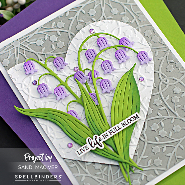 hand made greeting card with a gray background, white heart with an overlay of purple and green Lily of the valley flowers created with new card making supplies from Spellbinders