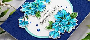 hand made card with a navy blue embossed background an oval center with blue watercolor magnolias and, and a happy mother's day sentiment created with card making supplies from Spellbinders