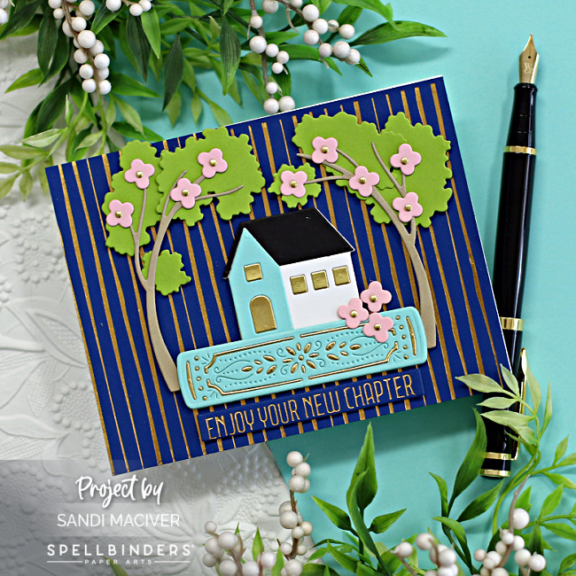 hand made card with a navy and gold striped background, a die cut house on a book and surrounded by die cut trees created with new card making products from Spellbinders