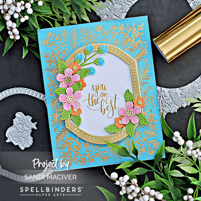 hand made mother's day card with a gold overlay background, and a white sentiment surrounded by pink and orange flowers created with card making supplies from Spellbinders 