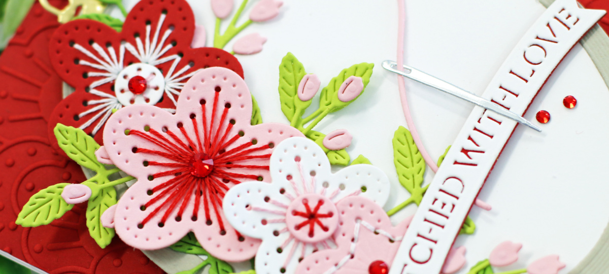 red pink and white hand made greeting card with stitched flowers and a wood looking embossing ring created with new card making supplies from SPellbinders 