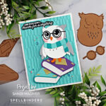 hand made card with a die cut owl with a blue scarf standing on top of a purple book created with new card making products from Spellbinders