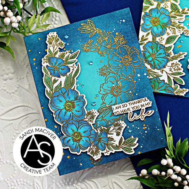 two tone teal card with a gold embossed overlay of flowers cascading down the left side of the card. Created with new card making supplies from Spellbinders