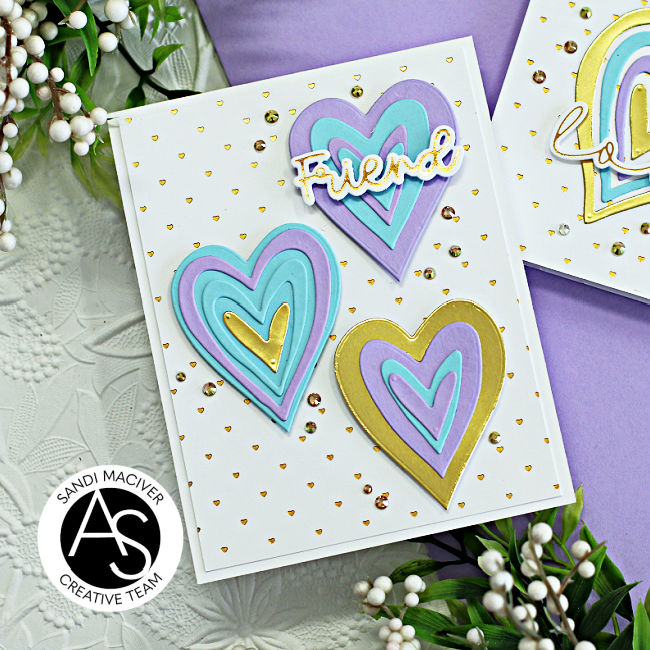 hand made card with a gold embossed heart white background and three purple and blue die cut hearts decorating the front created with new card making supplies from Alex Syberia Designs