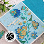 hand made greeting card with a embossed blue background and a die cut floral stem in greens blues and golds created with new card making products from Alex Syberia Designs