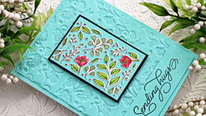 teal blue embossed card with a floral center and pink flowers, created with new card making products from Altenew