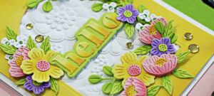 hand made white and yellow card with an arch cut in the center surrounded by pink yellow and purple die cut flowers created with new card making supplies from Spellbinders