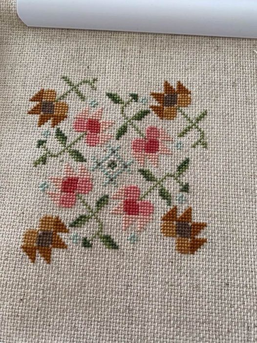 my first cross stitched biscornu, with a oatmeal colored base and pinks, greens and rust cross stitched pattern