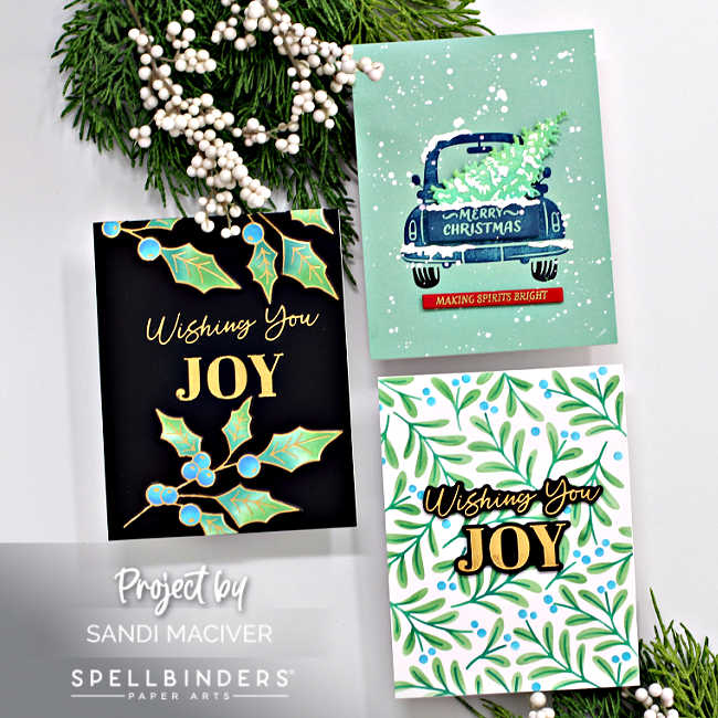 three hand made christmas cards in in black blue and green with gold highlights, a holly design, a vintage faded blue truck with a tree in the back and a stencilled holly pattern all created with new card making supplies from Spellbinders