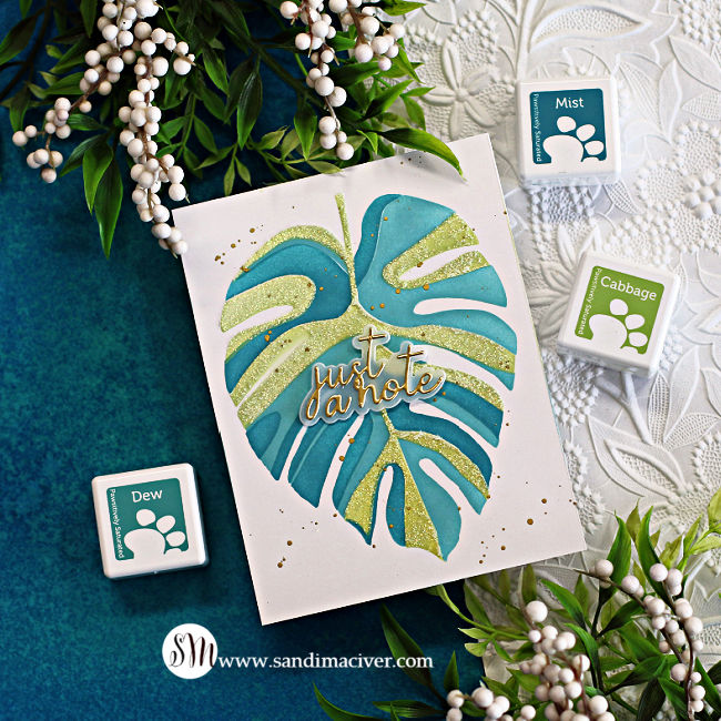 stenciled monstera leaf in three shades of teal on a white card background with a gold sentiment overlay, created with new card making supplies from Simon Says Stamp