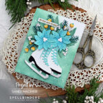 hand made Christmas card with white ice skates and a bouquet of greenery and blue flowers on a pale green splattered background created with new card making products from Spellbinders