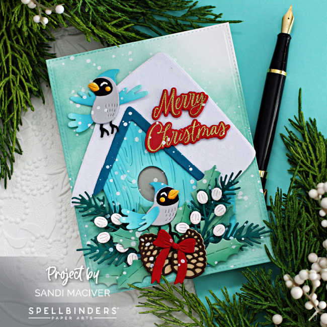 hand made christmas card with a teal snowcapped birdhouse, lots of green and white foliage, two blue and gray birds and red Merry Christmas sentiment created with new card making products from Spellbinders