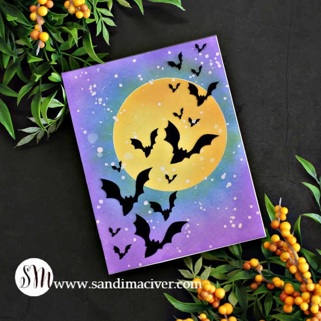 hand made Halloween card with a big yellow moon and a blue and purple sky with a flock of bats flying across it