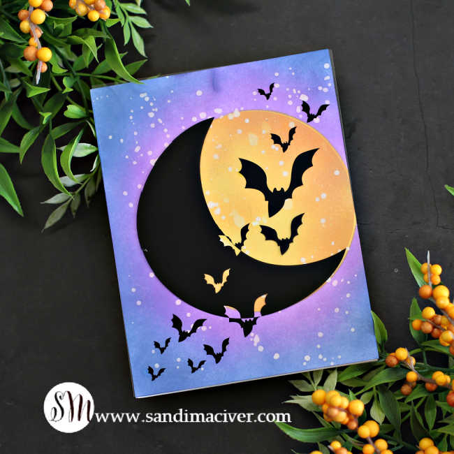 hand made Halloween card with a big yellow moon and a blue and purple sky with a flock of bats flying across it