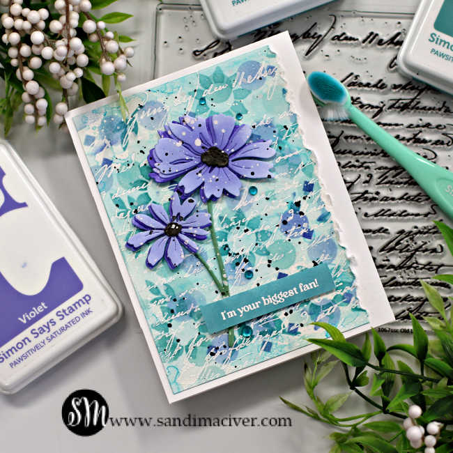 hand made card with a stenciled background in teal and purple with two die cut purple flowers overlaid