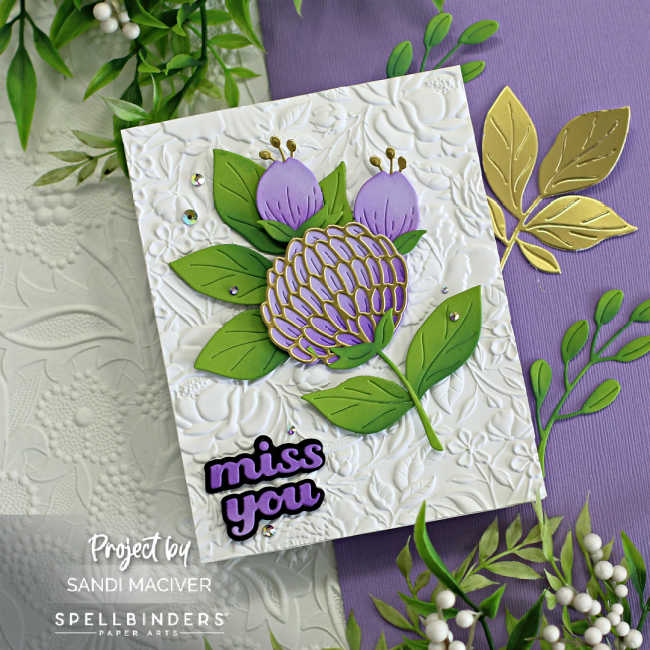 hand made card with a white floral embossed background and a large purple and gold flower with purple buds over two tone green leaves