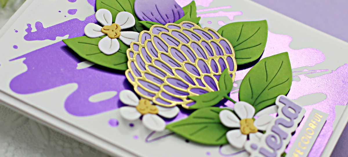 hand made card with a purple splash on white background, a die cut purple and gold flower and small white flowers