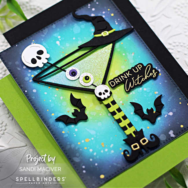 Halloween themed hand made card with a green martini decorated with eye balls, skeletons and a witches hat, with a green blue and purple ink blended background