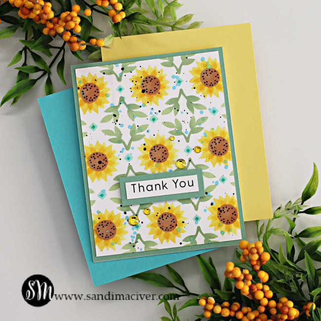 Hand made birthday card with stenciled sunflowers and leaves on a green card base and a green and white sentiment in the center