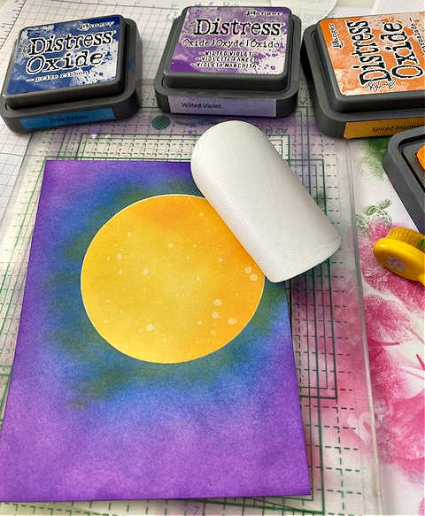 picture of the masking technique where the moon is covered with sticky paper while ink blending in purple and blue around it