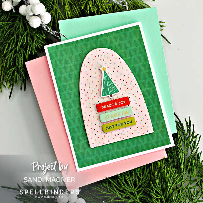 hand made christmas card with a green background, a pink star arch and a tiny green christmas tree with sentiment banners underneath