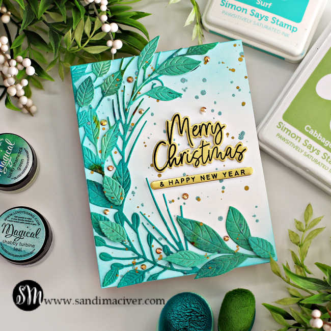 hand made die cut christmas card in blues with a leaf sprig up and around the left side and a gold and black holiday sentiment