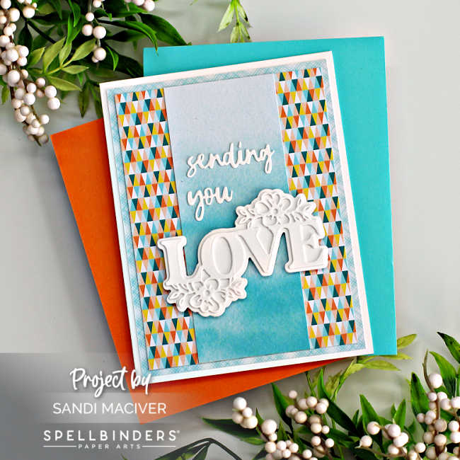 hand made wedding card with a multicolored background and a blue center with a die cut white sentiment overlay