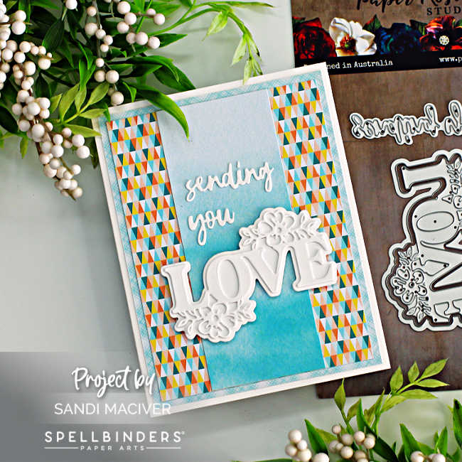 hand made wedding card with a multicolored background and a blue center with a die cut white sentiment overlay