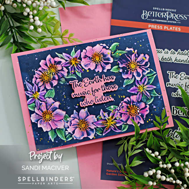 hand made floral card with pink and purple flowers, green leaves and a dark blue background with a pink and blue sentiment in the center