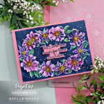 hand made floral card with pink and purple flowers, green leaves and a dark blue background with a pink and blue sentiment in the center