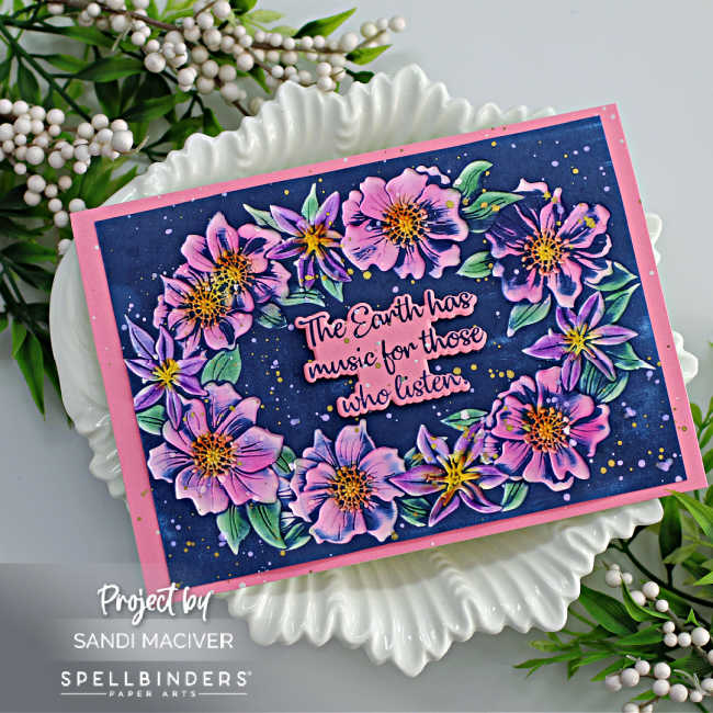 hand made floral card with pink and purple flowers, green leaves and a dark blue background with a pink and blue sentiment in the center