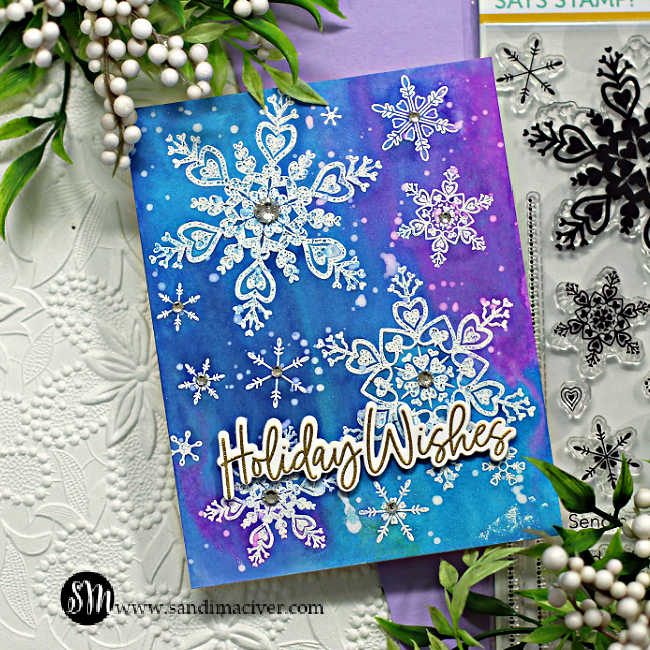 blue and pink hand made christmas card covered in white embossed snowflakes