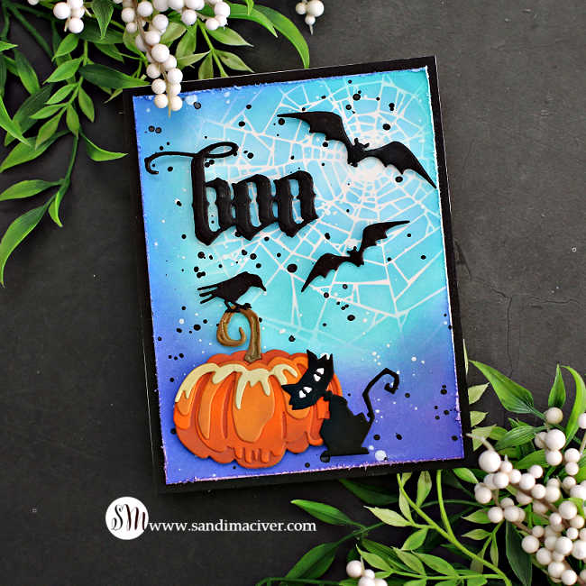 hand made Halloween card with a blue and purple background and stenciled spiderweb, a large orange pumpkin with a black cat in front of it and a crow sitting on the stem. The sky has black bats and a boo sentiment