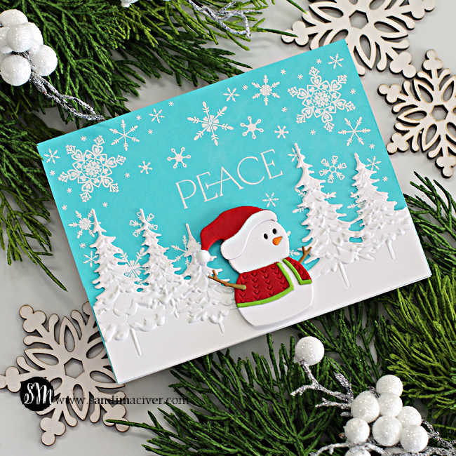 hand made christmas card in teal and white with white embossed trees and a die cut snowman in a red santa suite