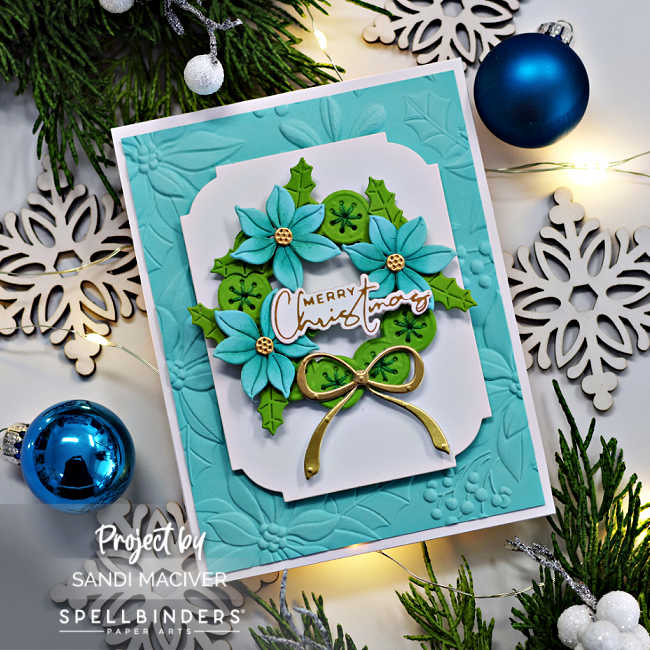 blue and green die cut christmas card with a die cut wreath, poinsettia and ivy leaves and a gold bow