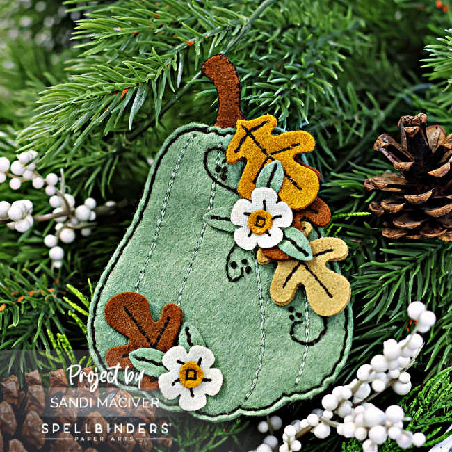 green and brown die cut and stitched felt pumpkin with leaves and flowers cascading down the right side.