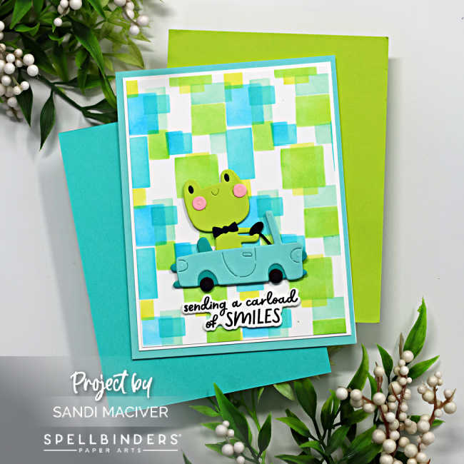 childs hand made birthday card with a blue and green stenciled square background and a green frog driving a turquoise car