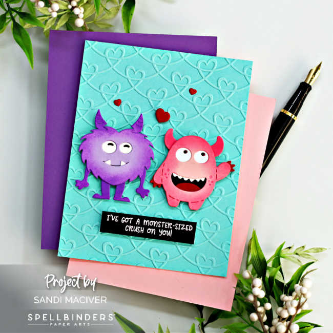 hand made teal card with a heart embossed background and purple and pink monsters