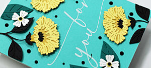 handmade turquoise card with yellow flowers and black leaves and a white sentiment in the center