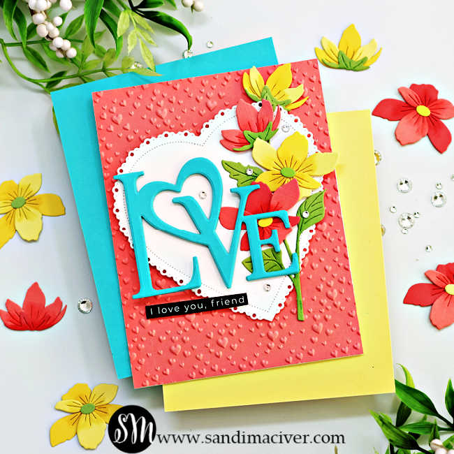 Peach heart embossed valentine's card with a teal die cut love in front of a white heart with a cascade of yellow and peach flowers down the right side