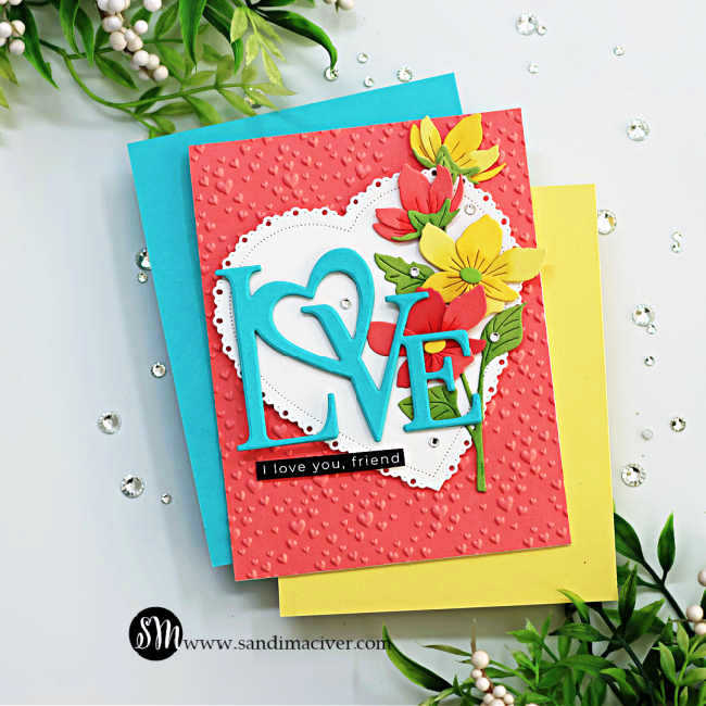 Peach heart embossed valentine's card with a teal die cut love in front of a white heart with a cascade of yellow and peach flowers down the right side