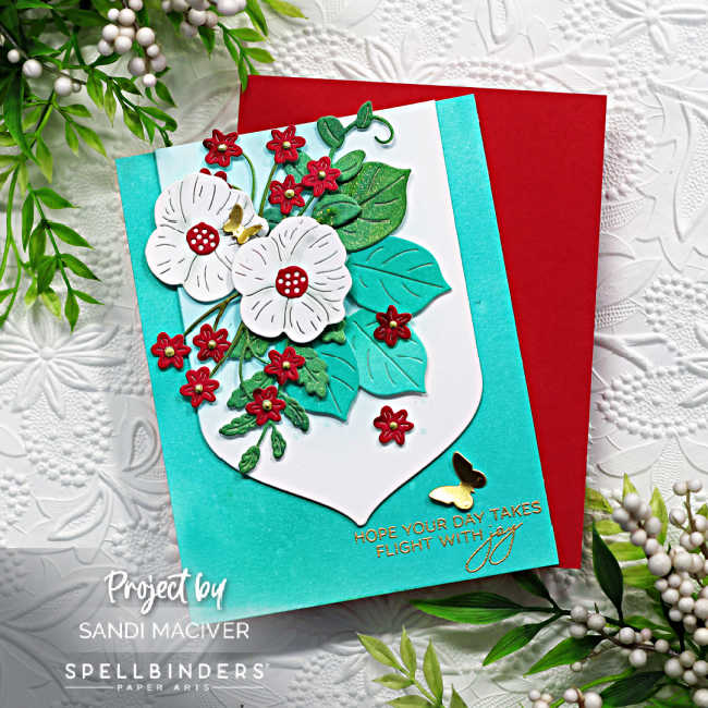 hand made floral card with white and red flowers on a bed of greenery with a turquoise blue background