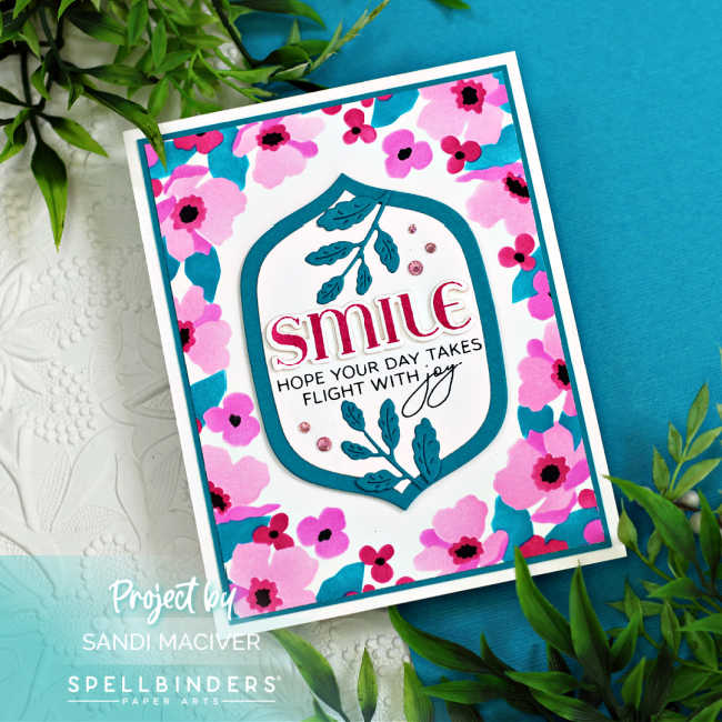 hand made card with a stenciled pink floral border with blue leaves, a center die cut two layer sentiment panel in white and teal with a pink sentiment, teal die cut leaves and pink rhinestones