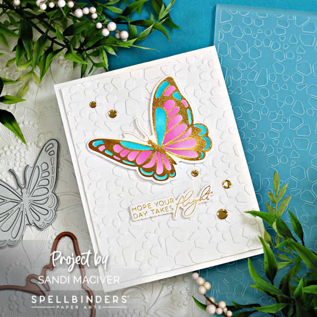 white hand made card with a white embossed background with a large foiled butterfly stenciled in pinks and blues with a gold and white glimmer foiled sentiment under it.