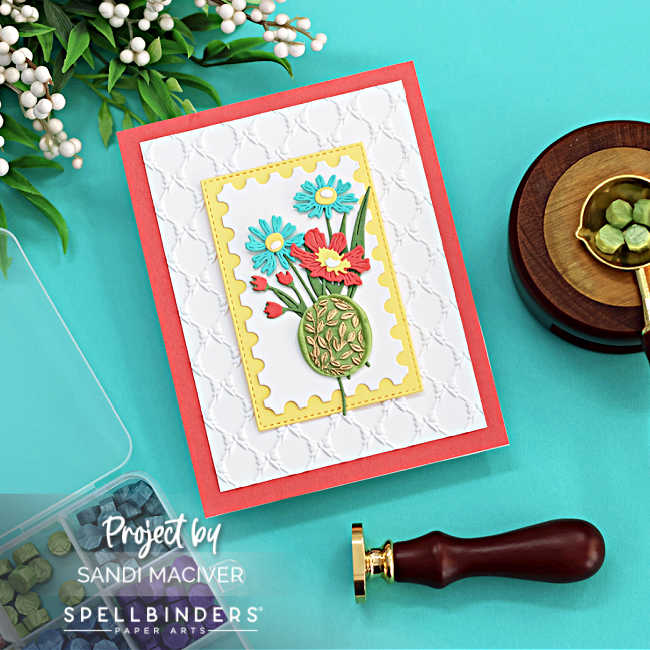 4 layered hand made card with an embossed background, a postage stamp die cut center with die cut flowers and a green wax seal with gold leaves.